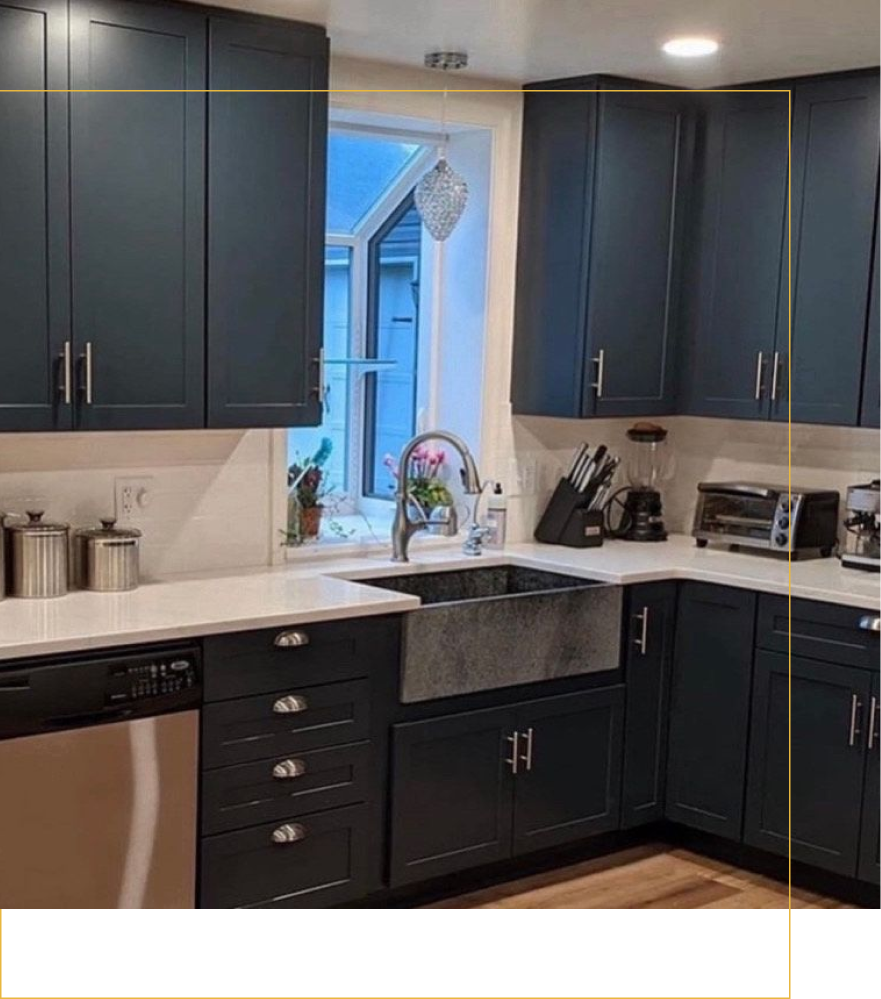 A kitchen featuring deep blue cabinets, white countertops, a farmhouse sink, and a window with a glass pendant light.