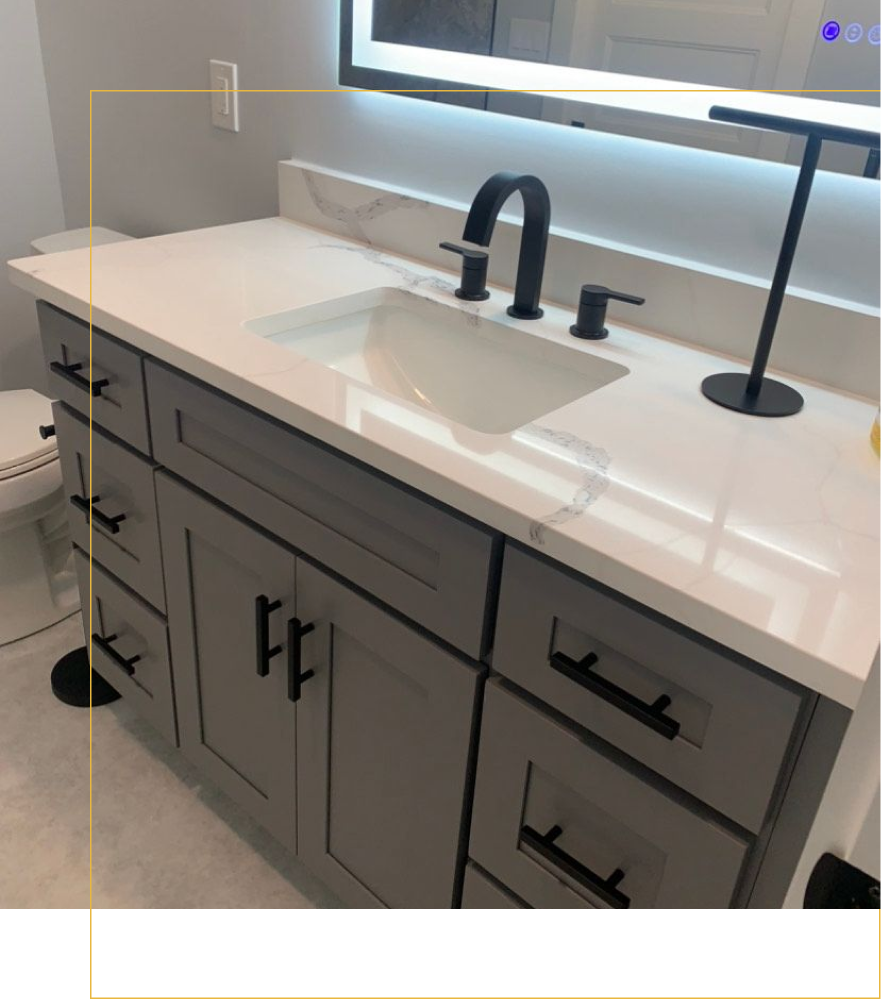 A gray bathroom vanity with a white marble countertop, black hardware, a modern faucet, and an LED-lit mirror above.