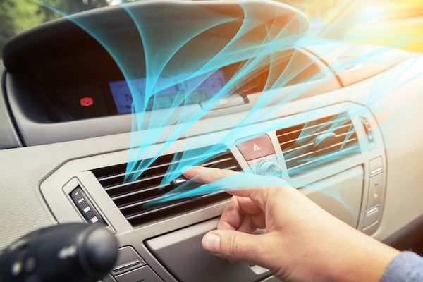 Hand adjusting car dashboard air vents with blue airflow lines illustrating cool air circulation | Cruz-N-Carz