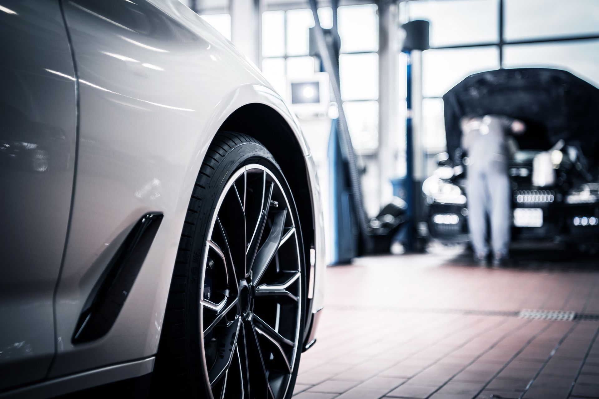 White car in auto shop with mechanic working in the background | Cruz-N-Carz