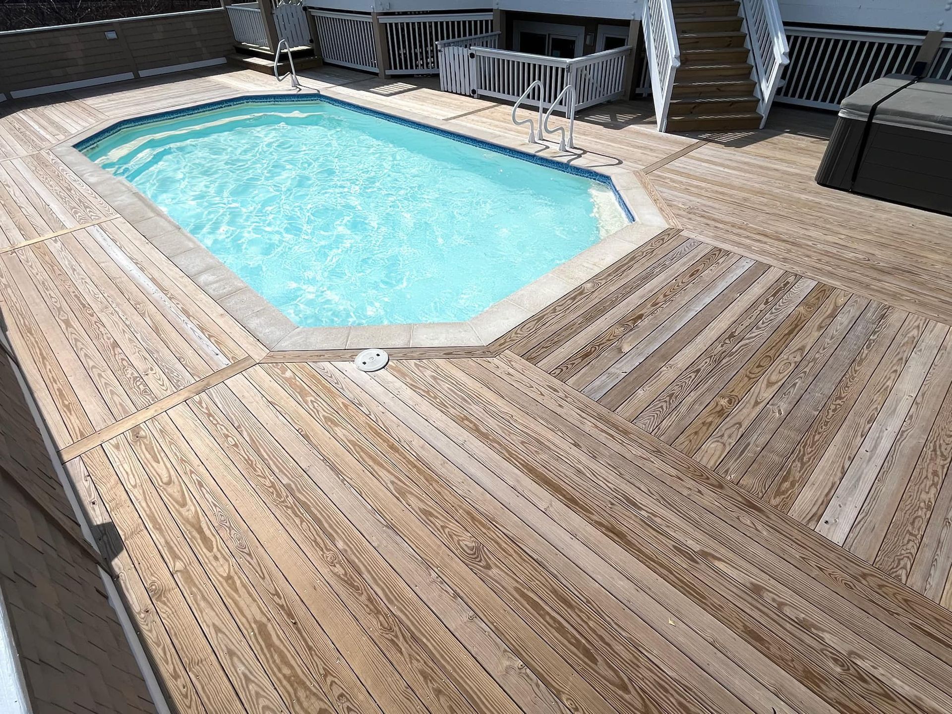 Wooden deck with small pool, surrounded by stairs and a white railing.