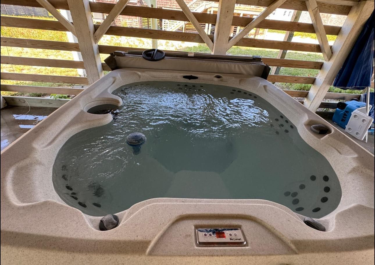 Hot tub filled with water under a wooden pergola.