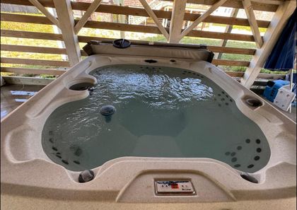 Hot tub filled with water under a wooden pergola.