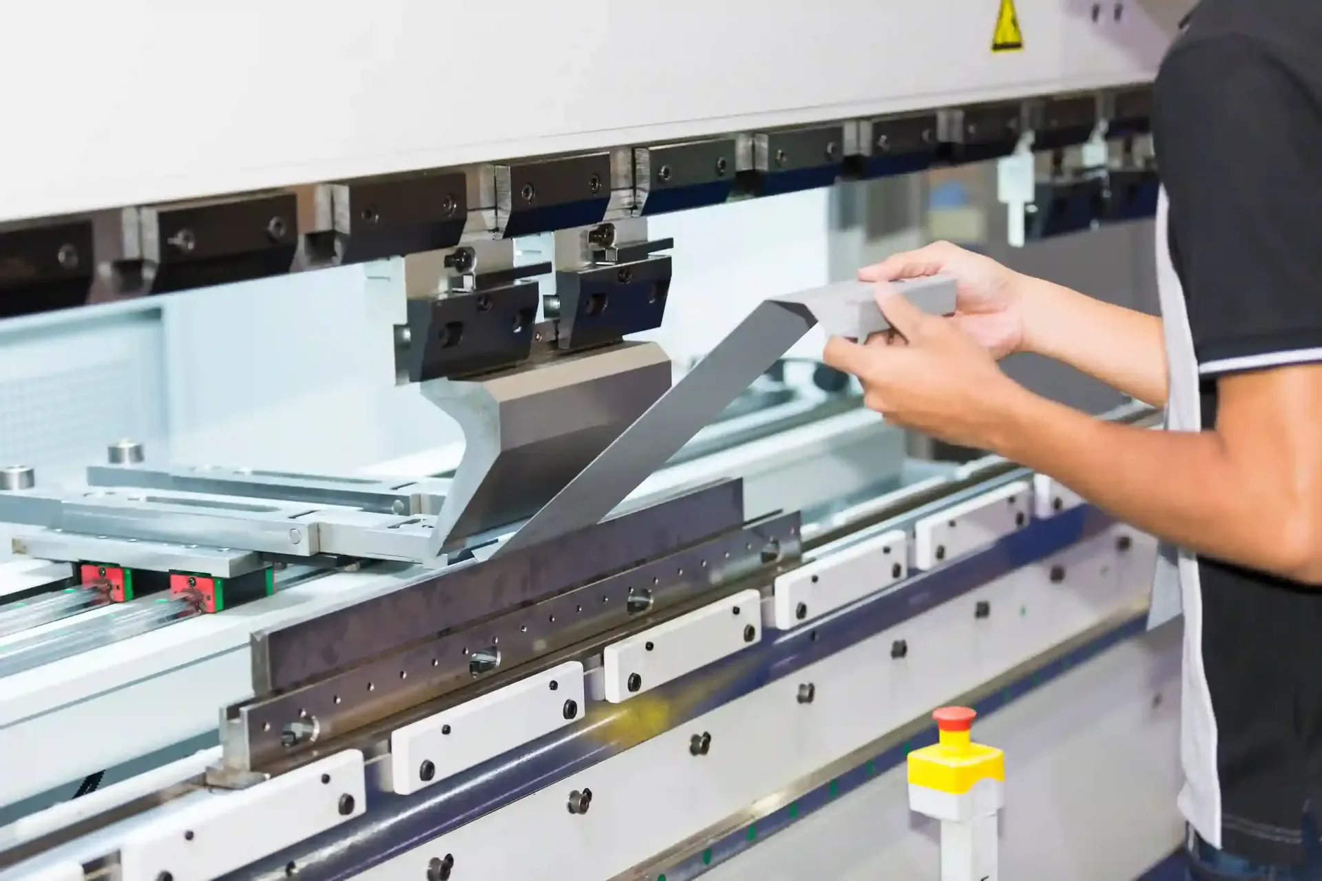 A press brake operator forming a precise bend in a sheet of metal, showcasing professional metal ben