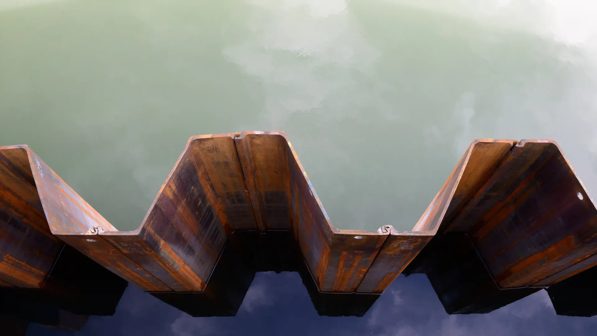 Corroded steel sheet piling exposed to water, demonstrating the importance of a protective metal spr