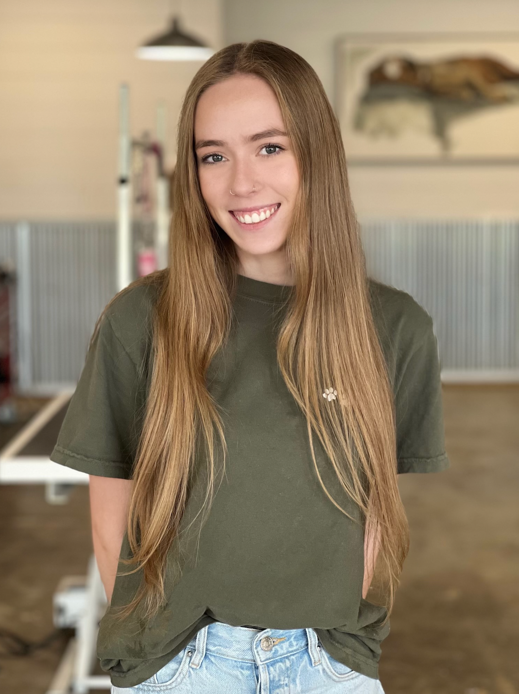 A young woman with long hair is wearing a green t-shirt and jeans.