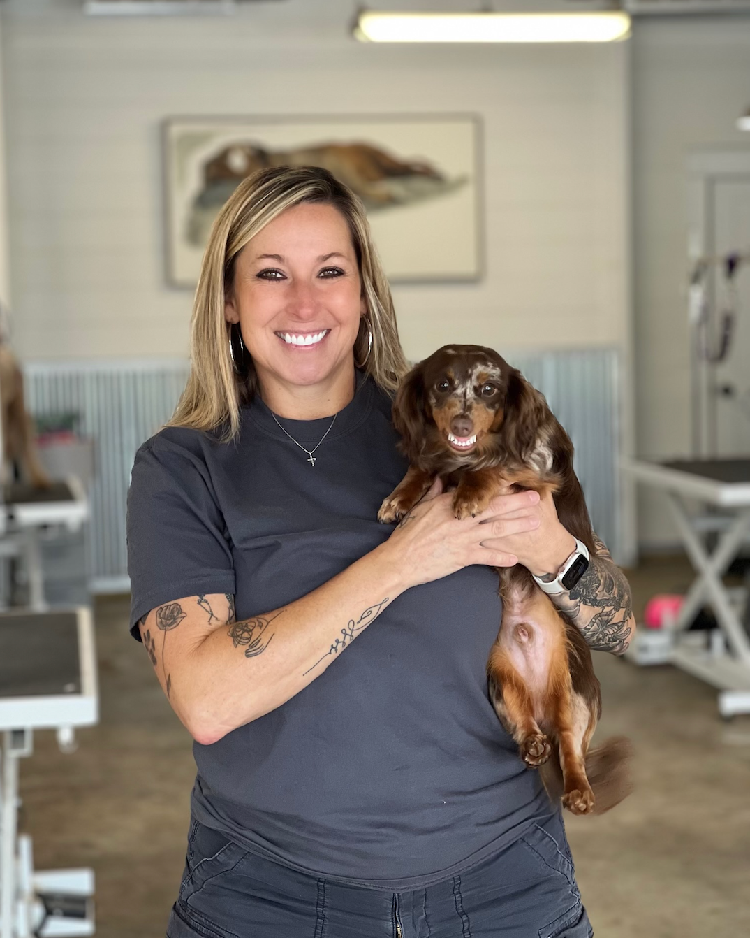 A woman is holding a small brown dog in her arms.