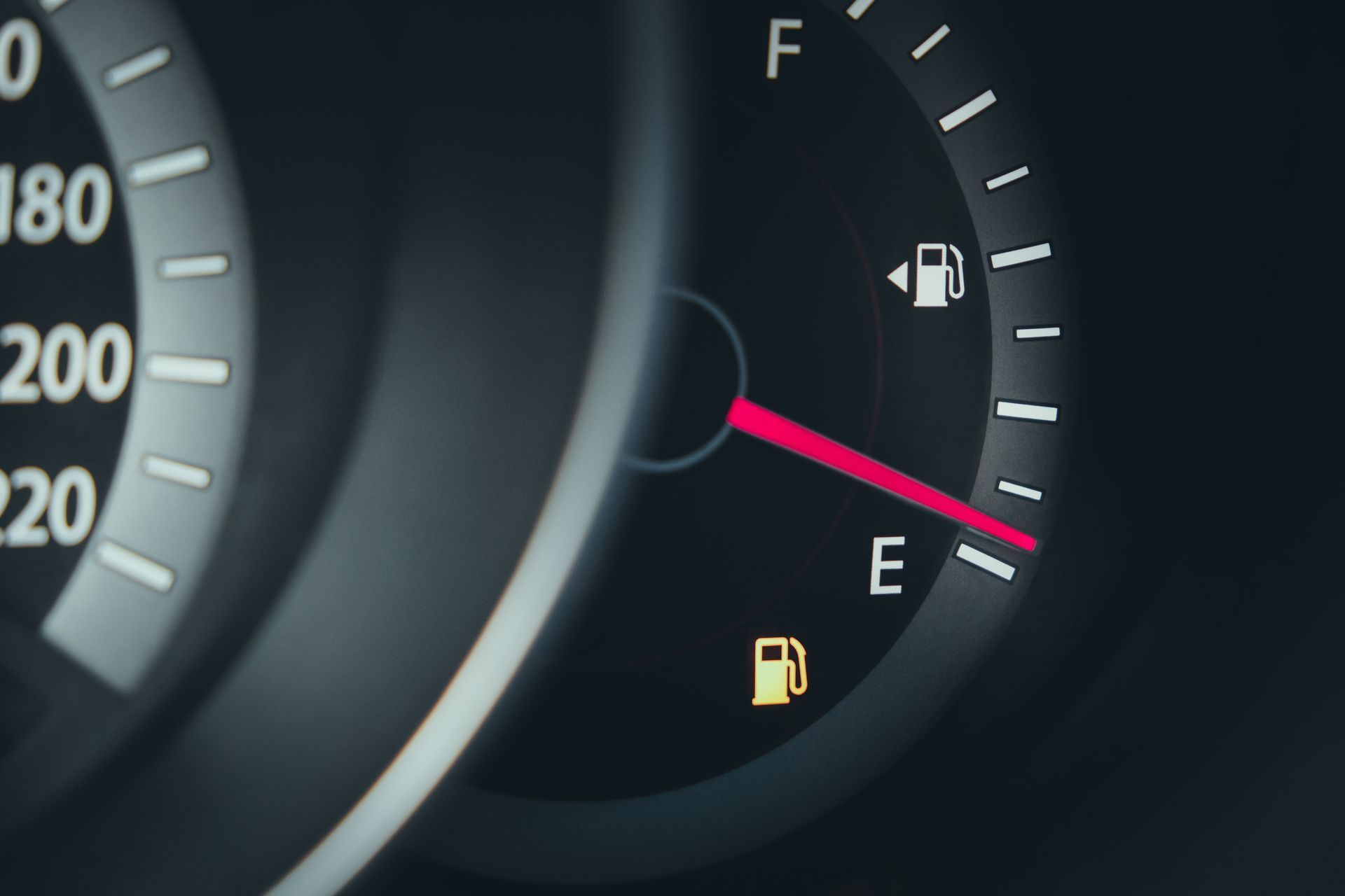 A car dashboard showing fuel gauge close to empty with warning indicator lit.