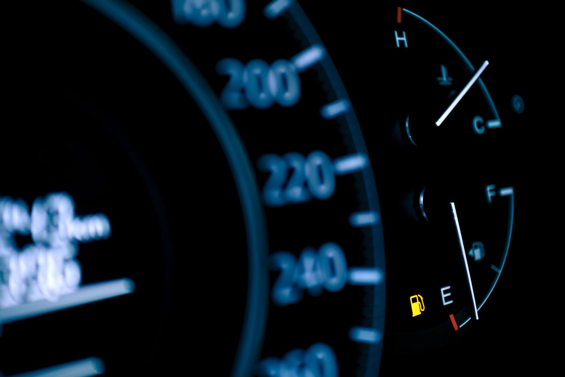 Close-up of car dashboard gauges showing speedometer and low fuel warning icon. Close-up of car dashboard gauges showing speedometer and low fuel warning icon.