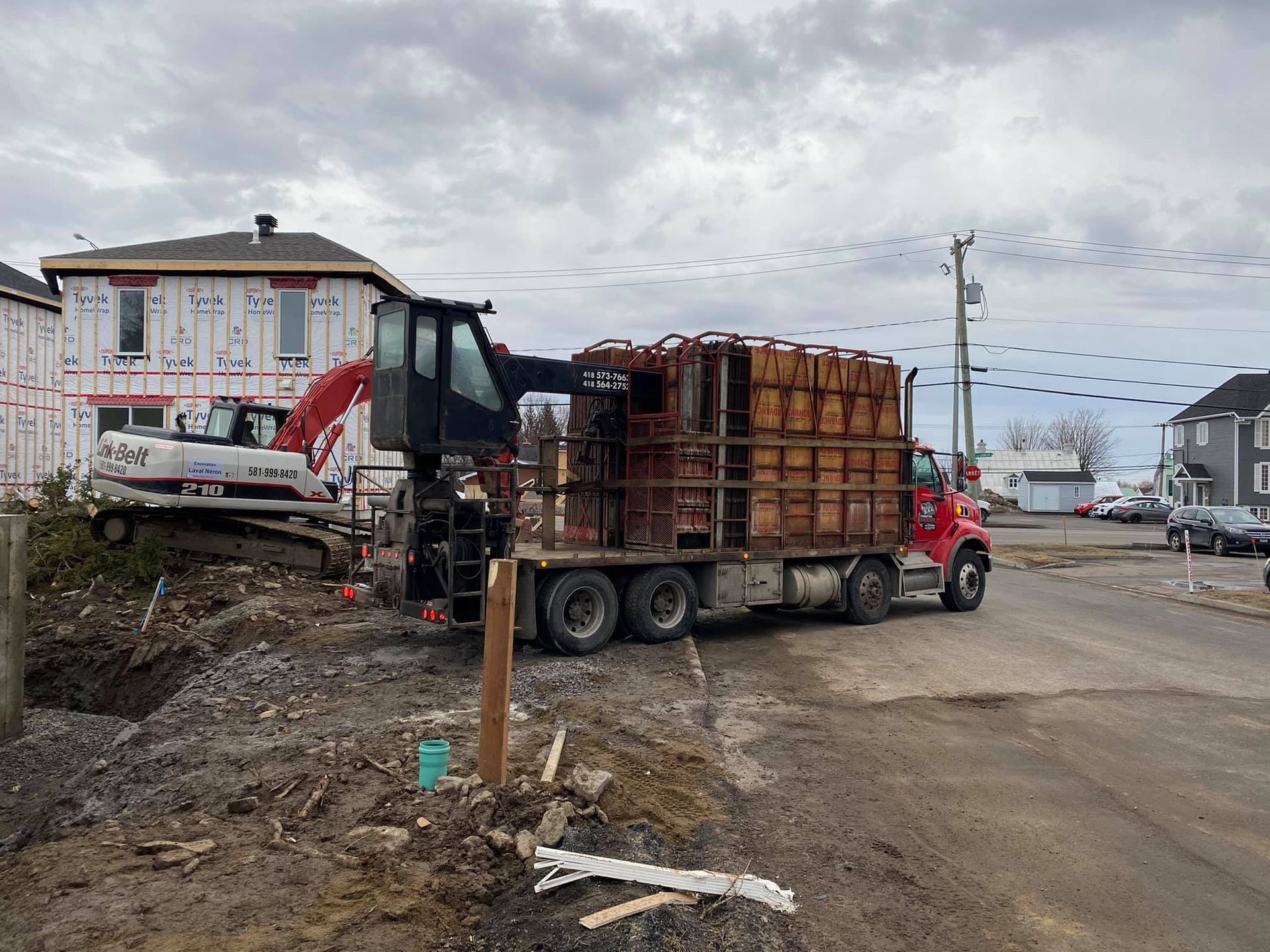 Un camion rouge transporte des briques sur un chantier de construction.