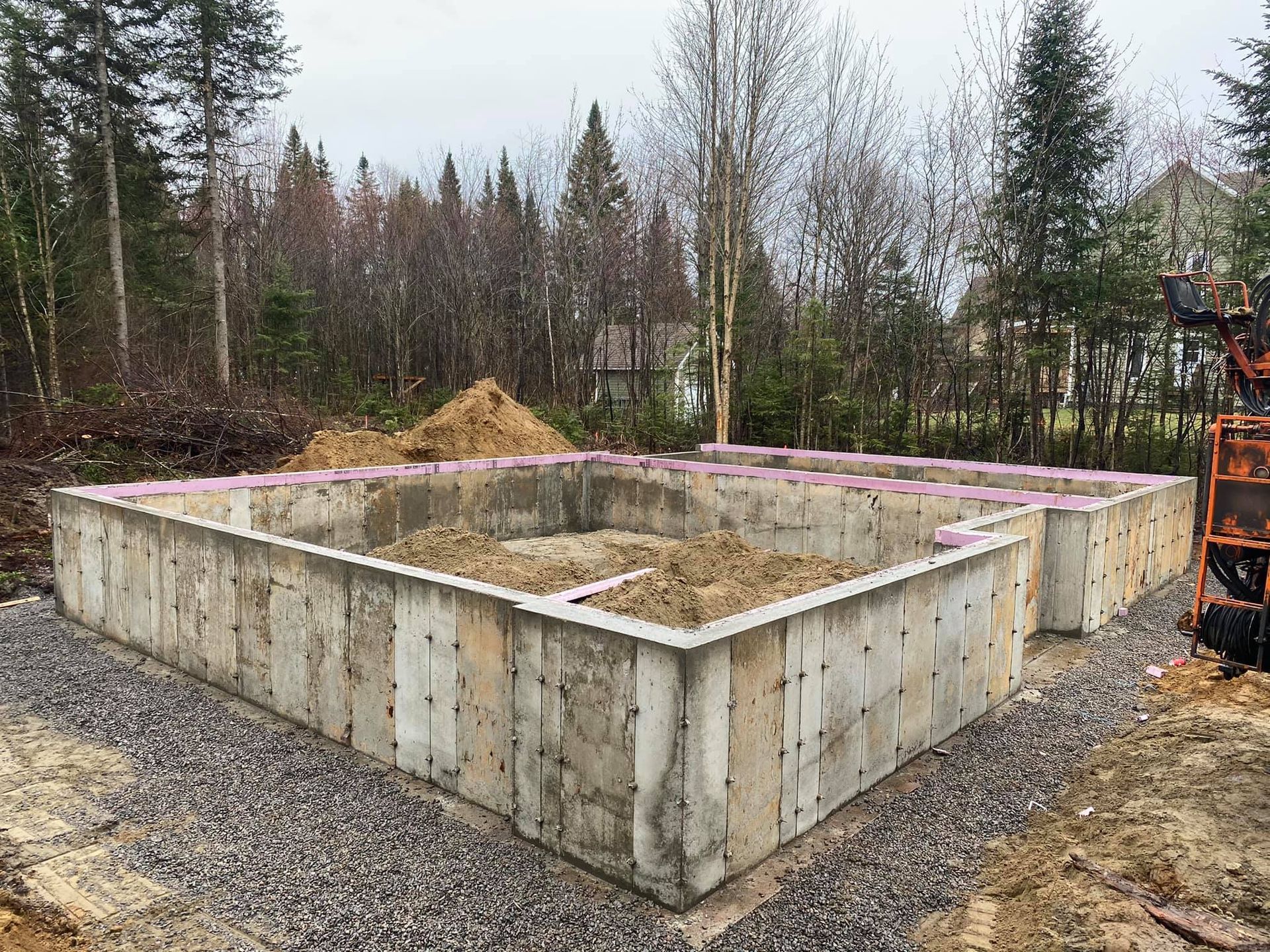 Une grande fondation en béton est en cours de construction au milieu d'une forêt.