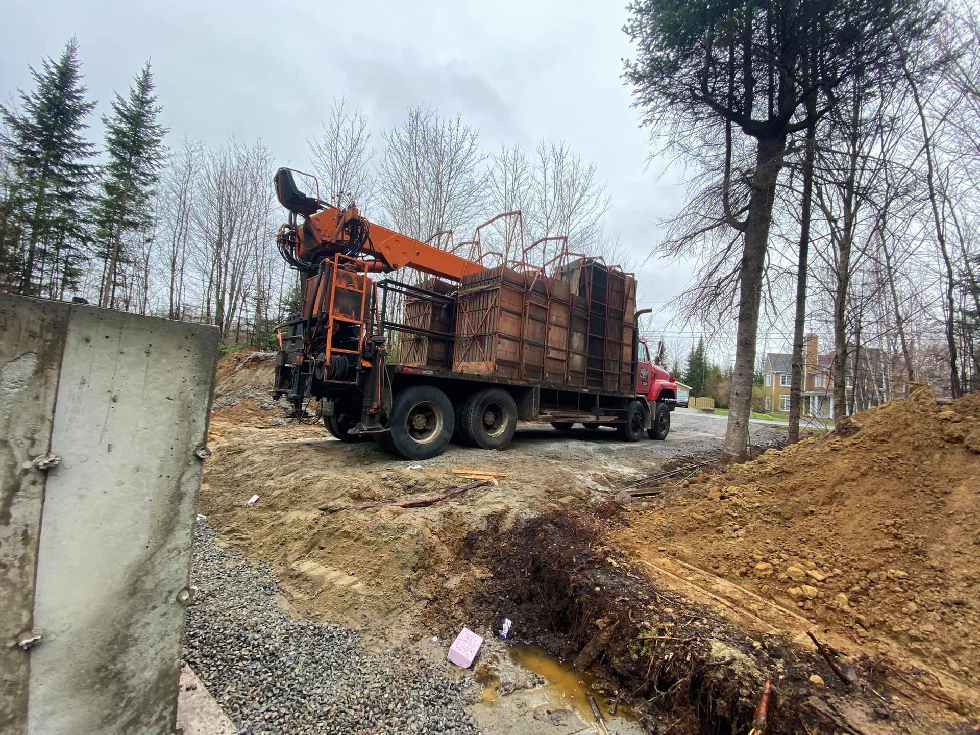 Un camion à benne rouge est garé sur le bord d'un chemin de terre.