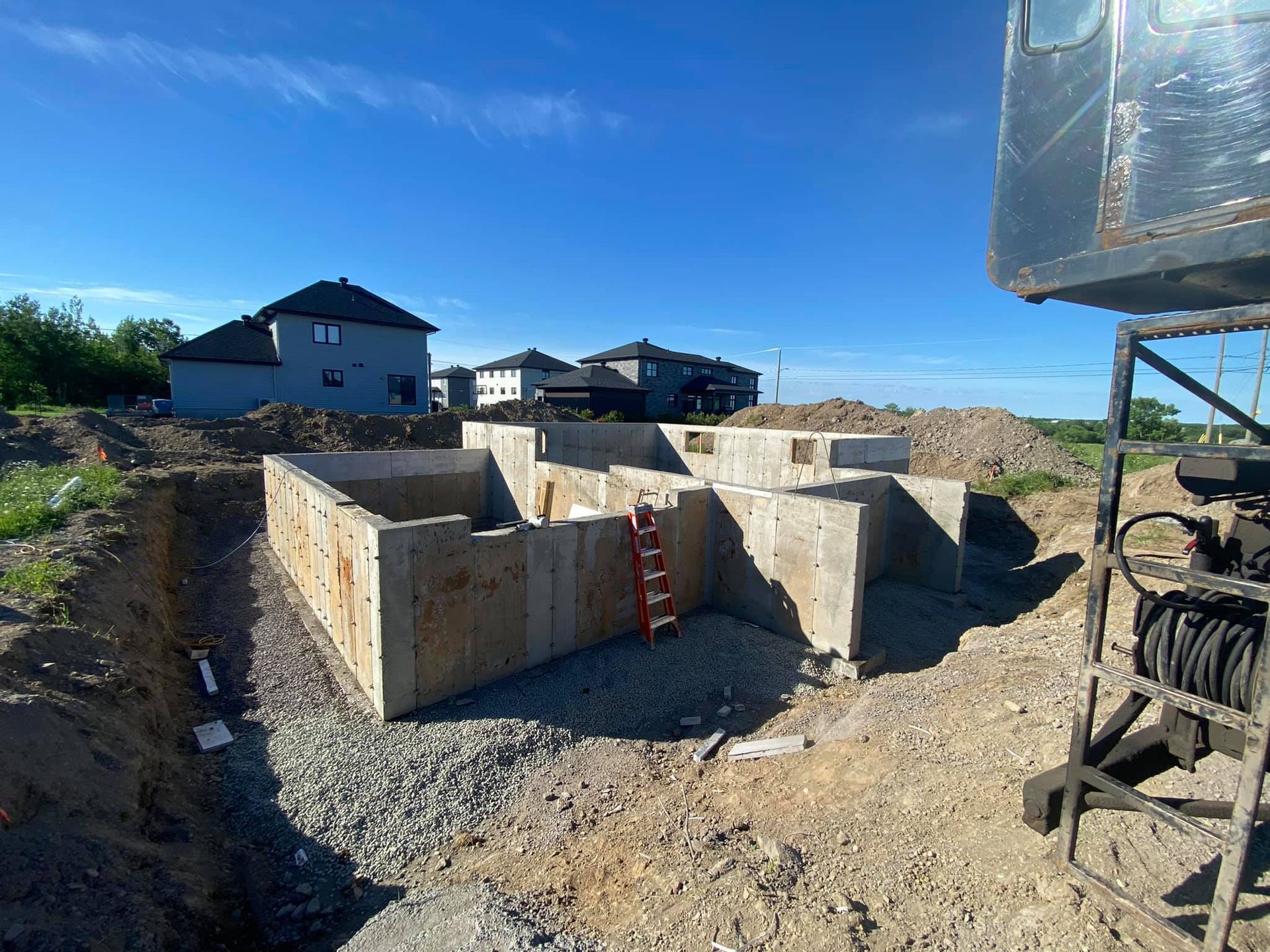 Une grande fondation en béton est en cours de construction dans un champ de terre.