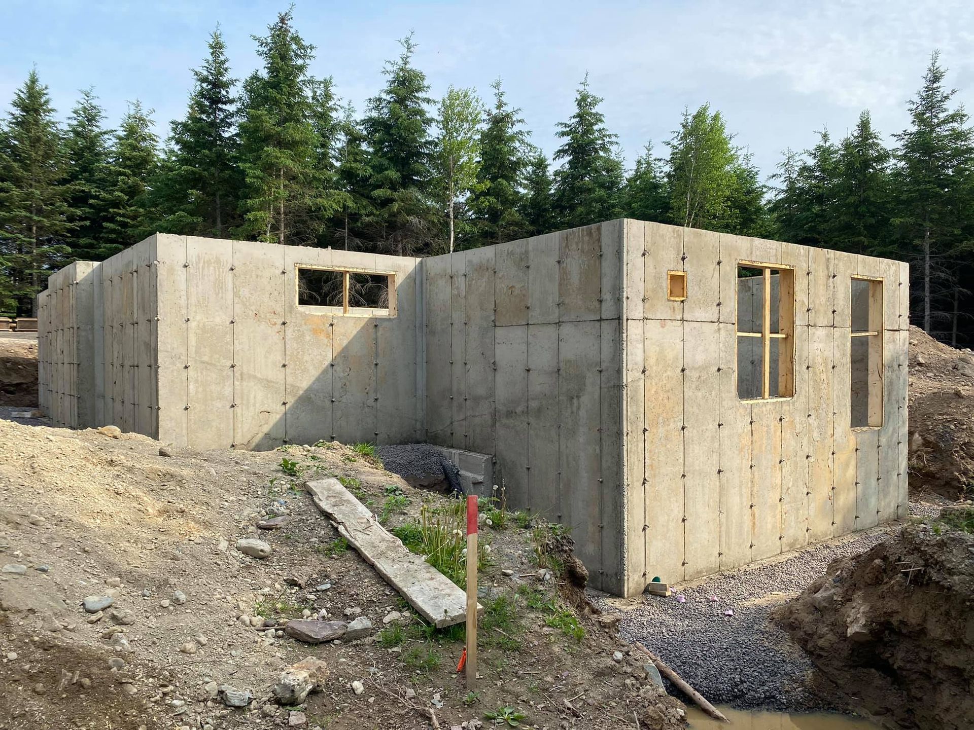 Une maison en béton est en construction au milieu d'une forêt.