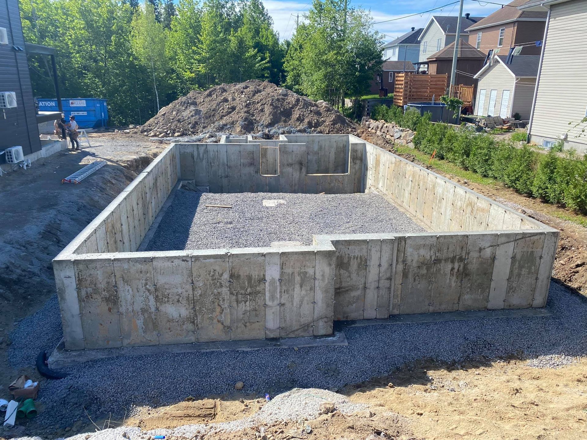 Une grande fondation en béton est en cours de construction dans l'arrière-cour d'une maison.
