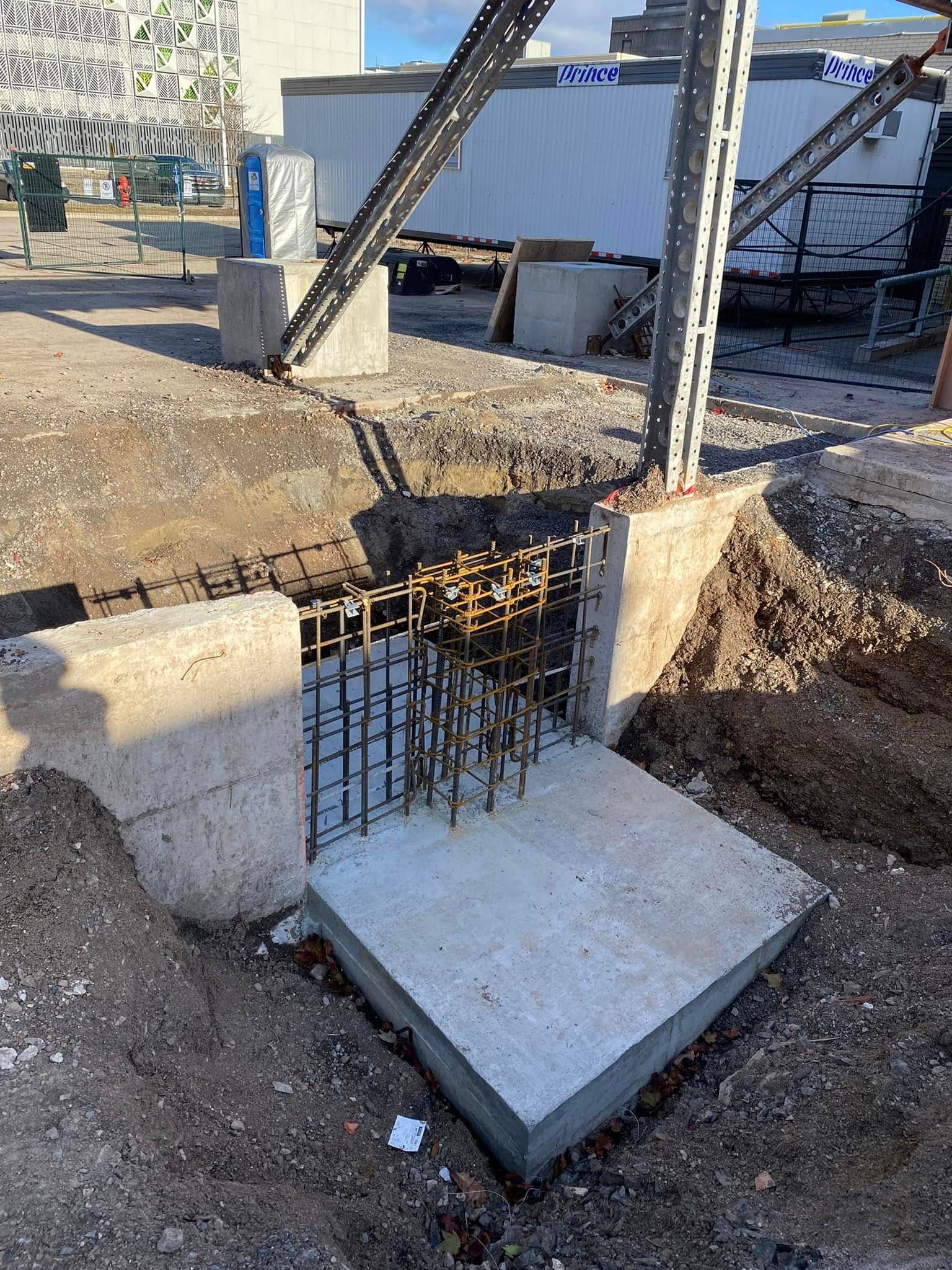 Un bloc de béton est posé dans la terre à côté d'un poteau métallique.