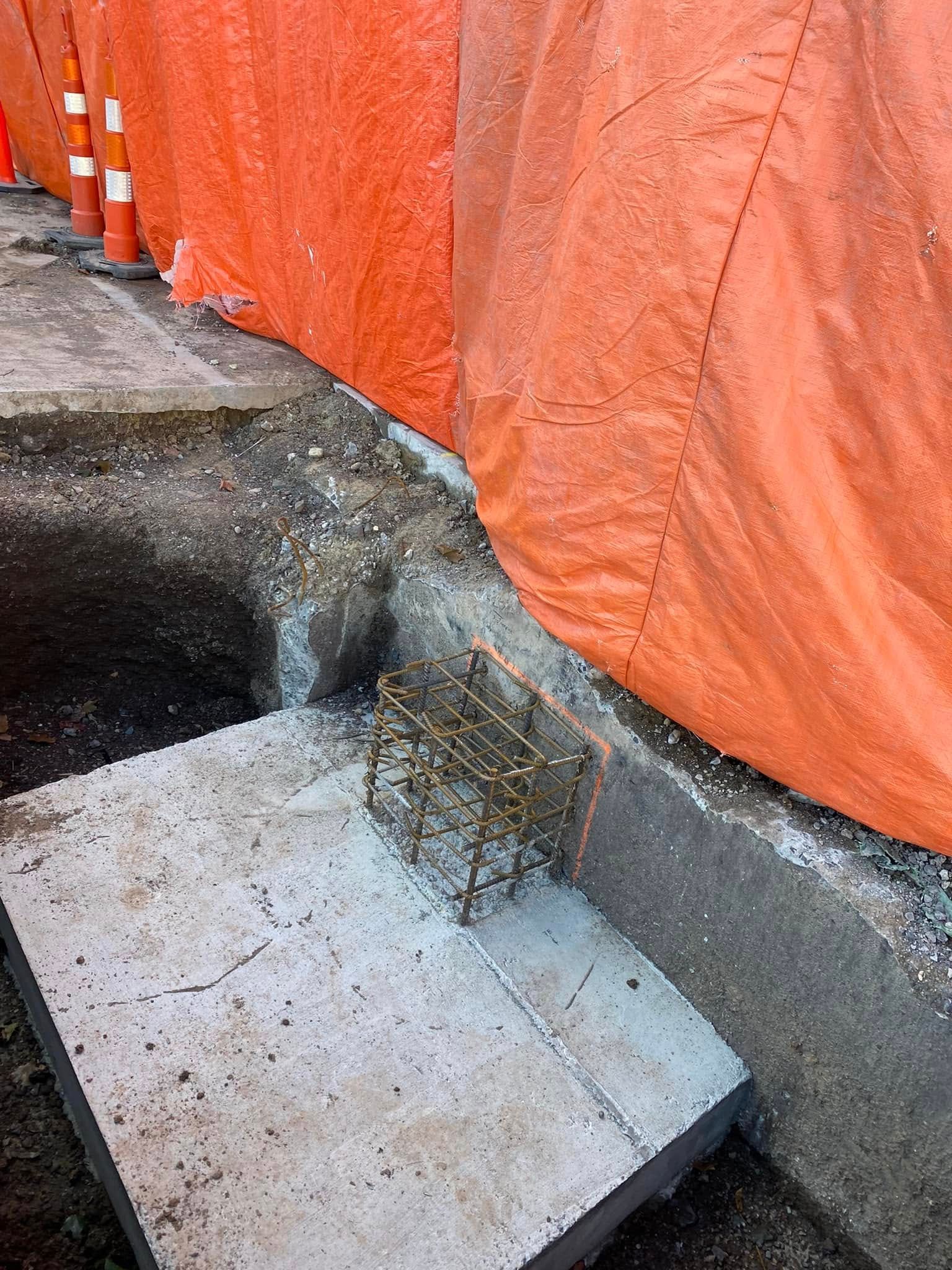Une dalle de béton est posée sur le sol devant une bâche orange.