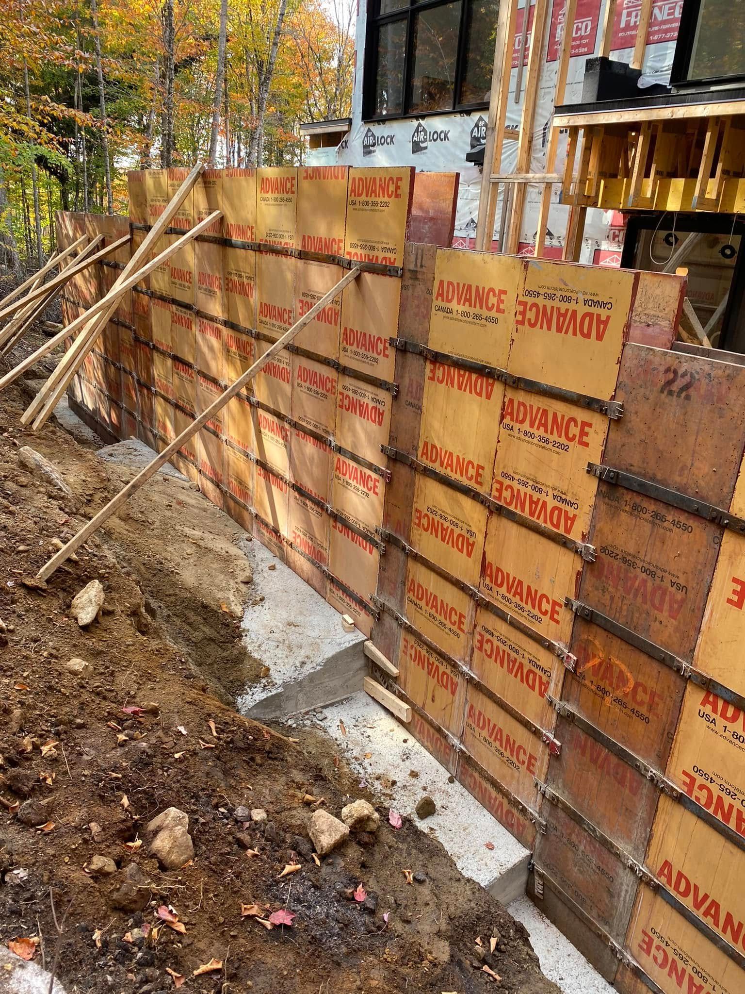Un mur en béton est en cours de construction à côté d'un bâtiment.