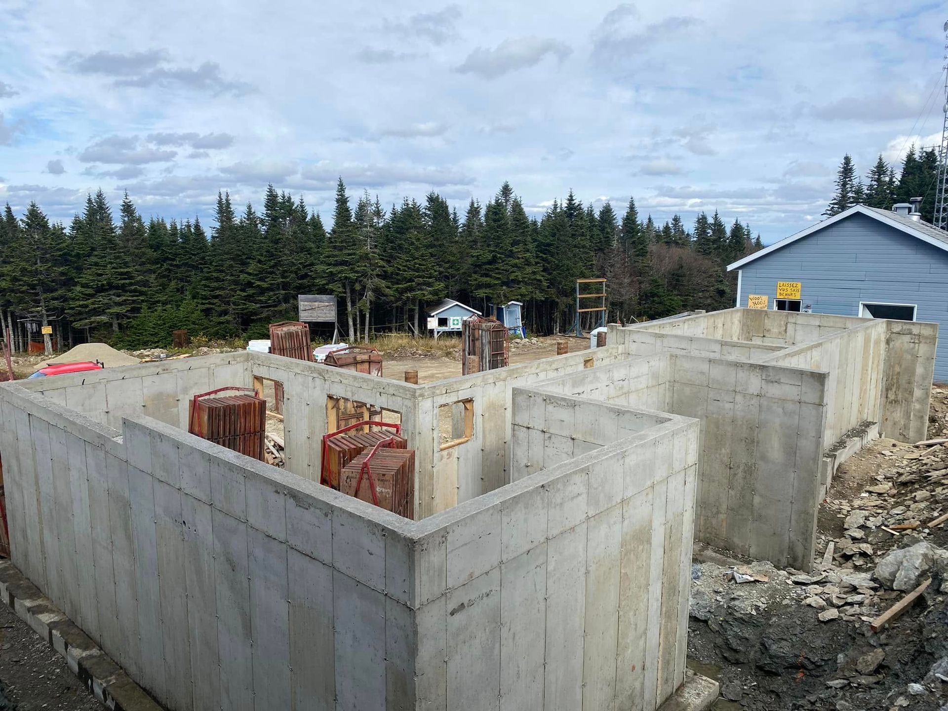 Un sous-sol en béton en construction avec une maison en arrière-plan.