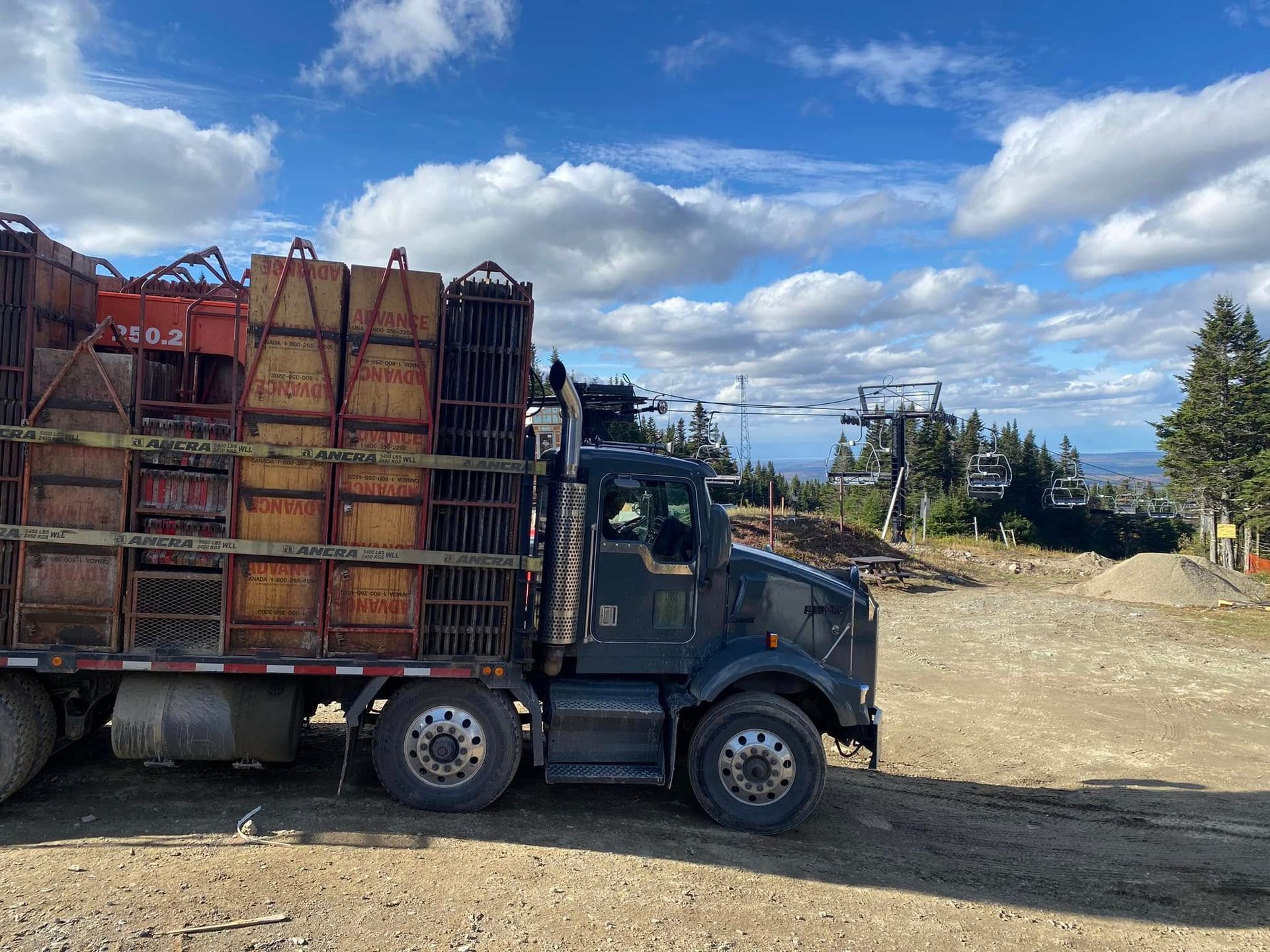 Un semi-remorque est garé sur un terrain en terre avec des caisses à l'arrière.