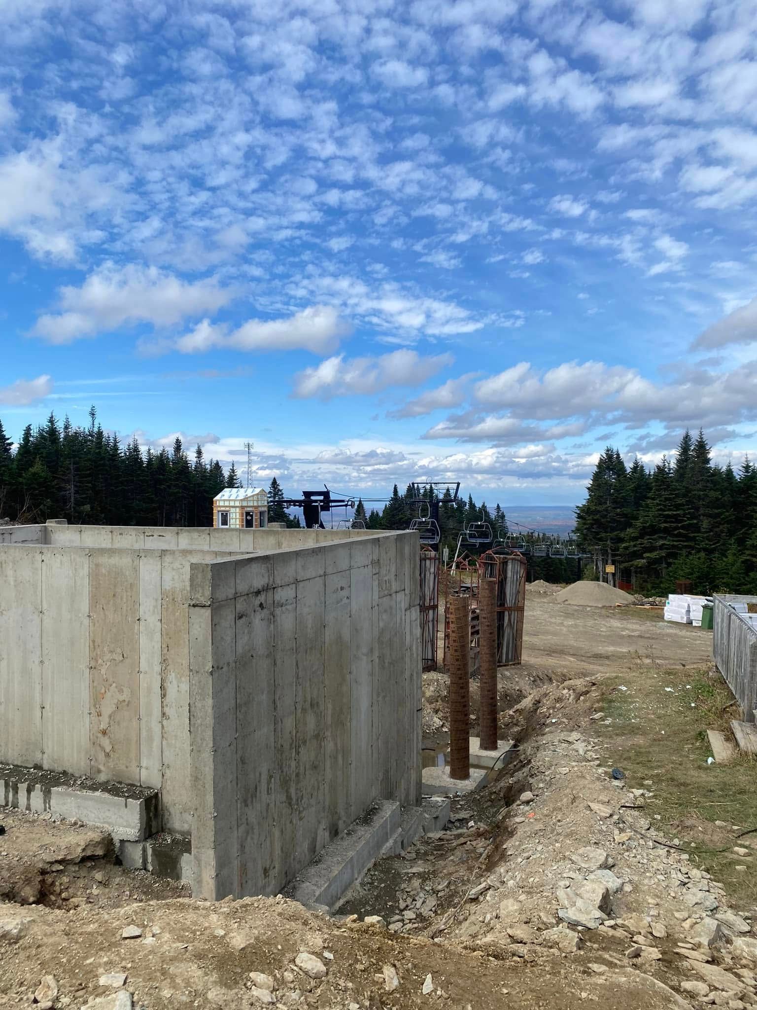 Un mur de béton est en cours de construction à côté d'un chemin de terre.