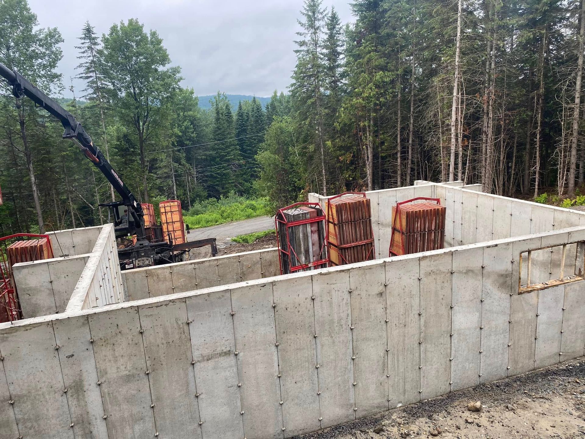 Un grand mur de béton est en train d'être construit au milieu d'une forêt.