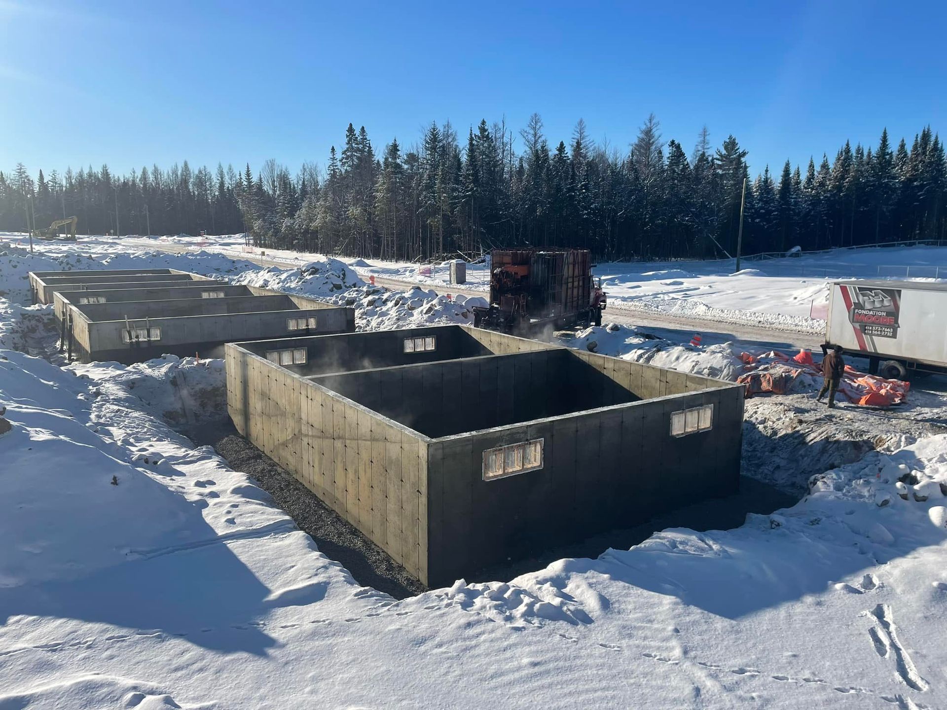 Une grande structure en béton est en cours de construction dans la neige.