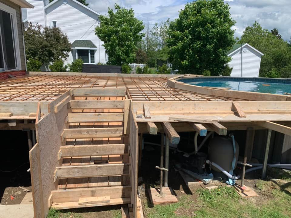 Une terrasse en bois est en cours de construction à côté d'une piscine.