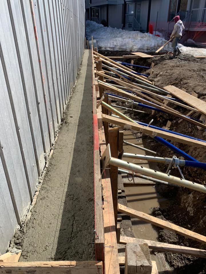 Un homme creuse un trou dans le sol à côté d'un bâtiment en construction.