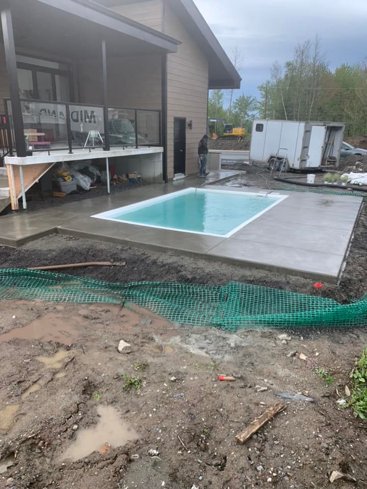 Une grande piscine est en cours de construction dans l'arrière-cour d'une maison.