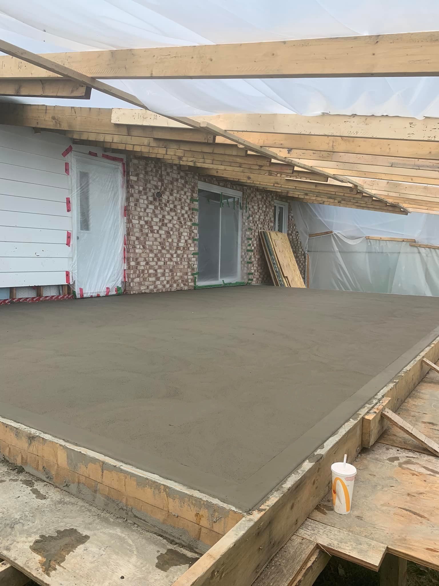 Un sol en béton est en train d'être coulé devant un bâtiment en construction.