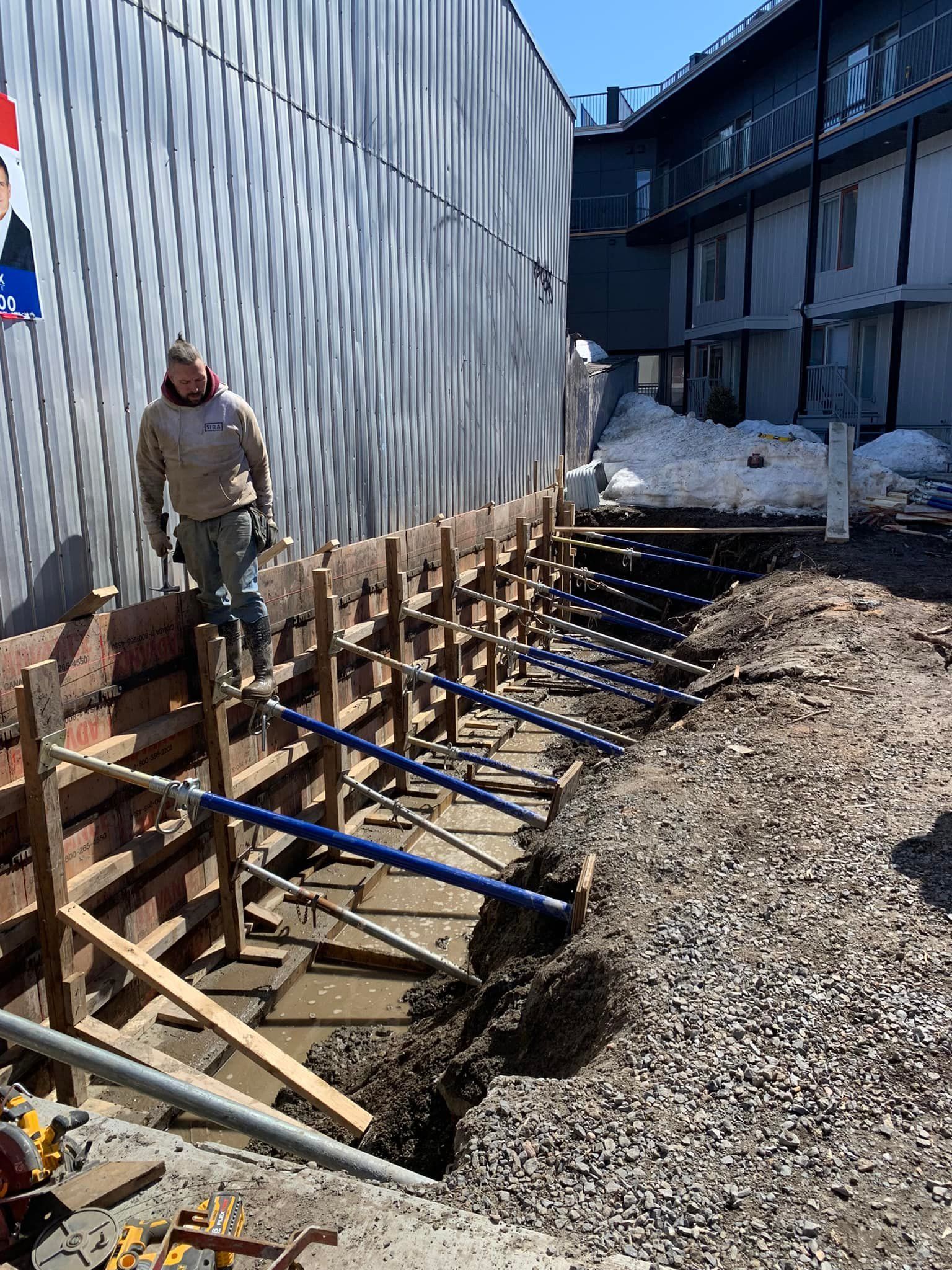 Un homme travaille sur un mur en béton devant un bâtiment.