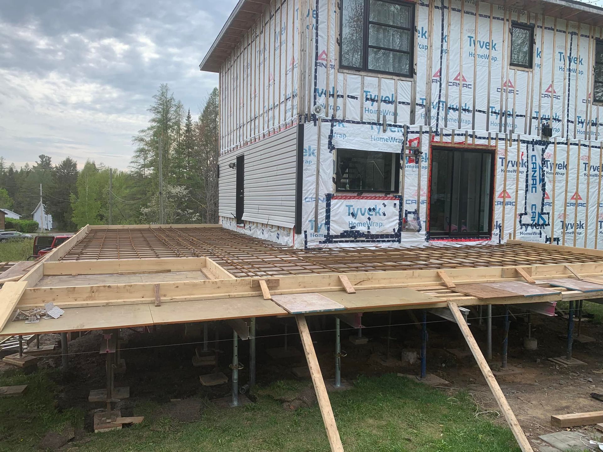 Une maison est en construction sur pilotis avec une terrasse en bois.