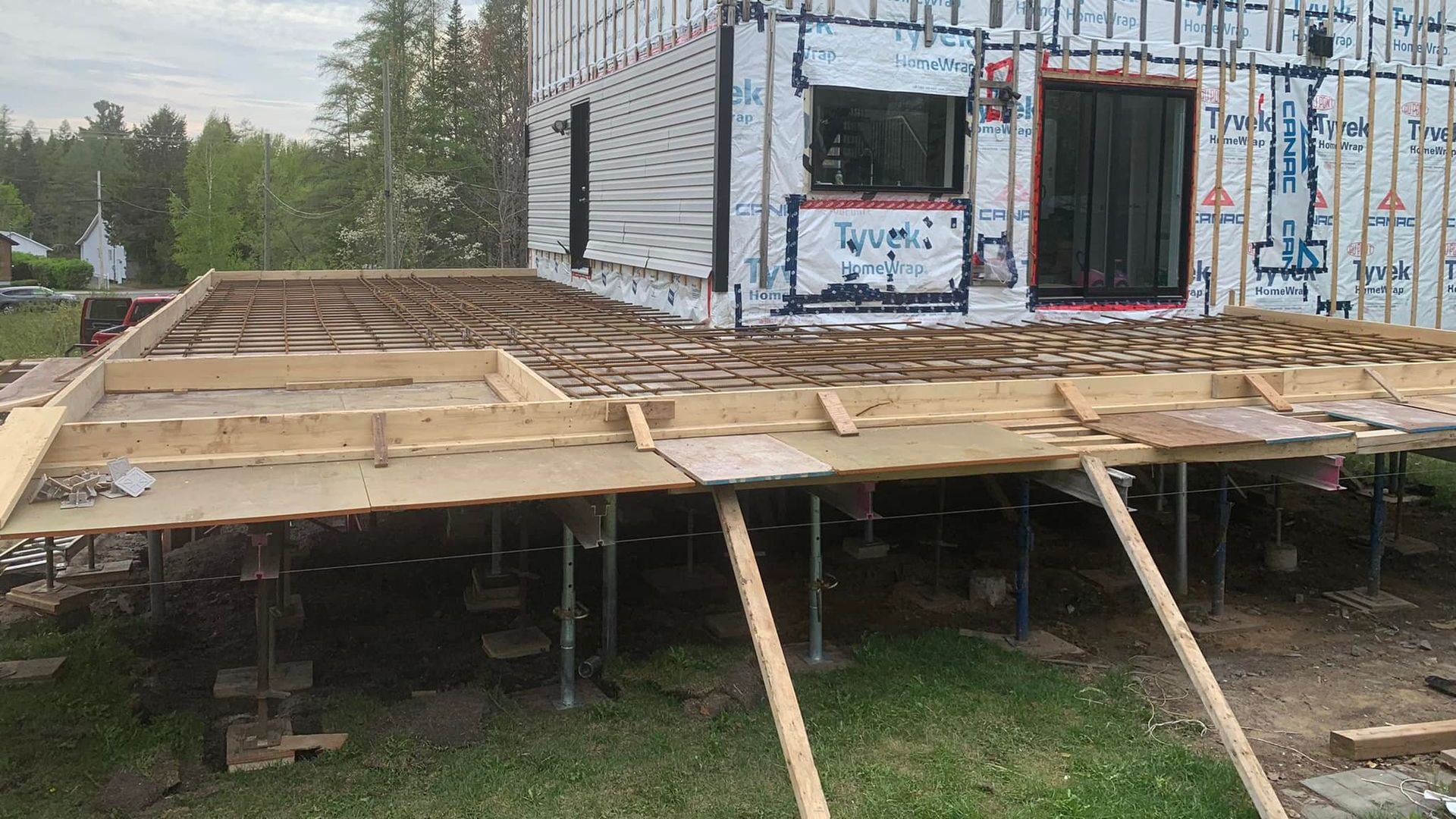 Une maison est en train d'être construite sur pilotis dans une cour.