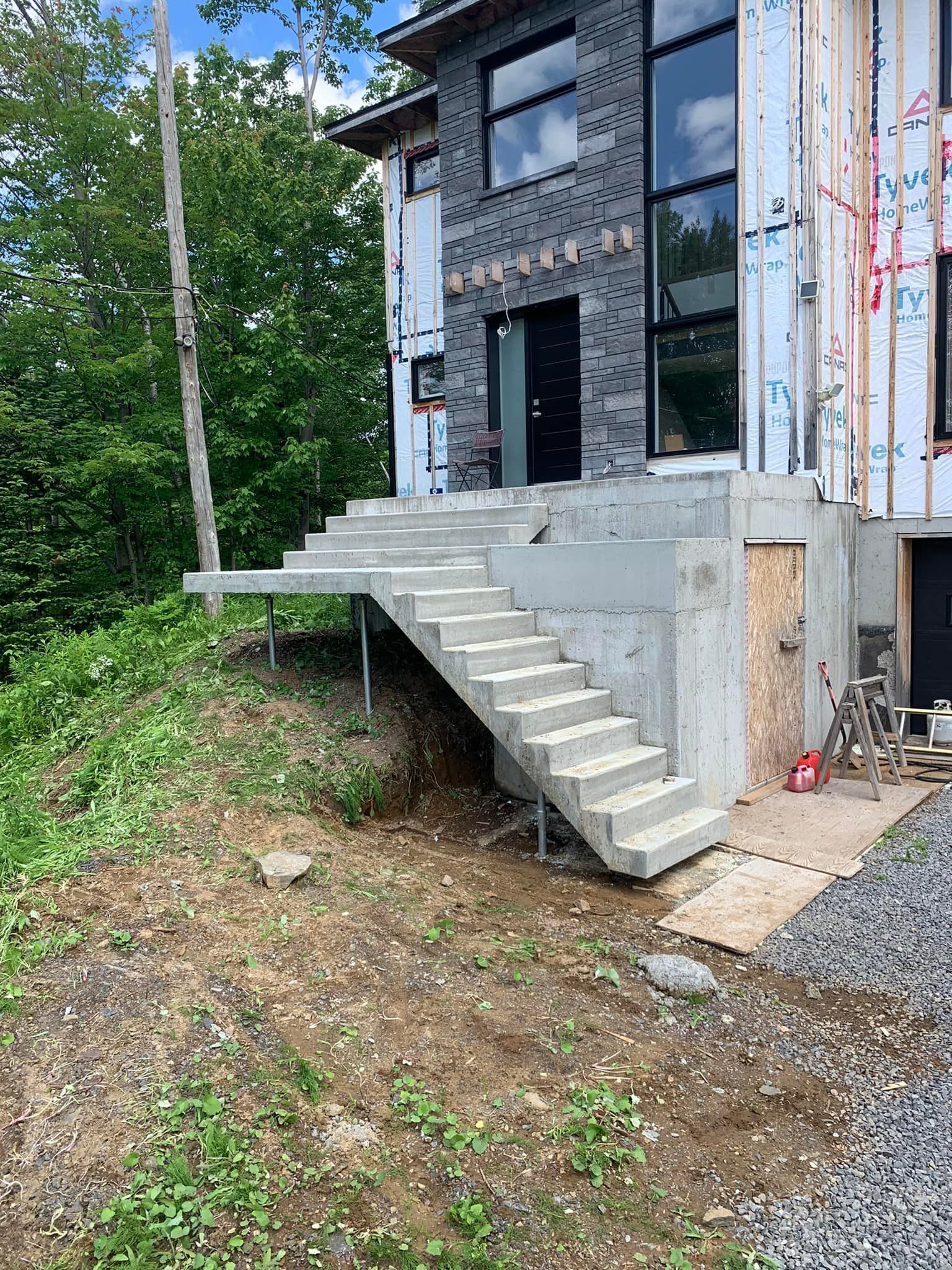 Un escalier en béton est en cours de construction devant une maison.