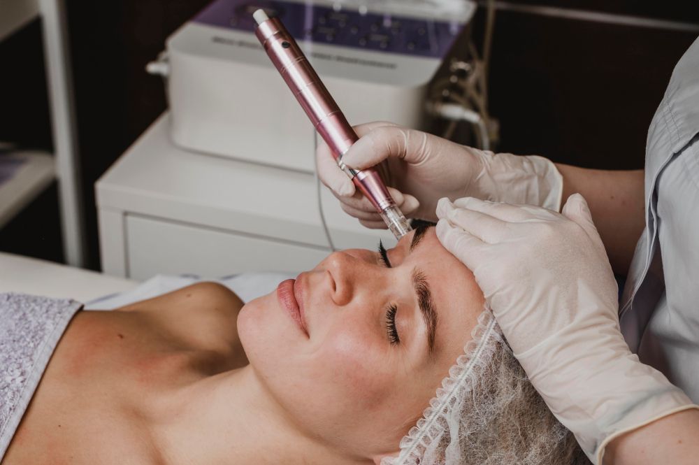A young woman getting a microneedling facial at a spa.