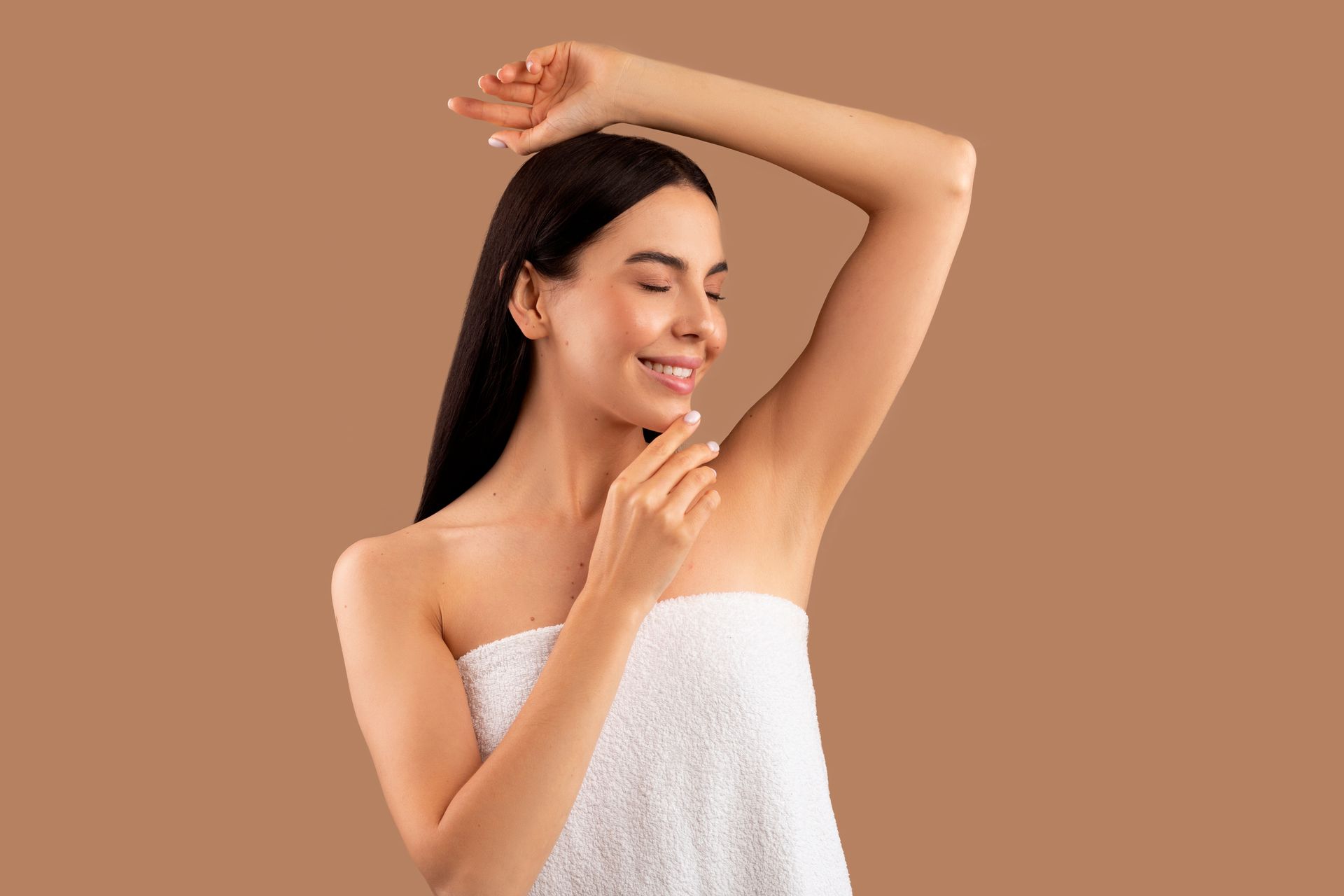 a woman wrapped in a white towel is smiling and touching her armpit