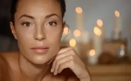 a woman touches her face with her hand and looks at the camera