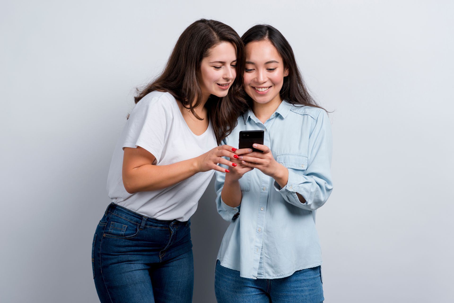 two women are looking at a cell phone together