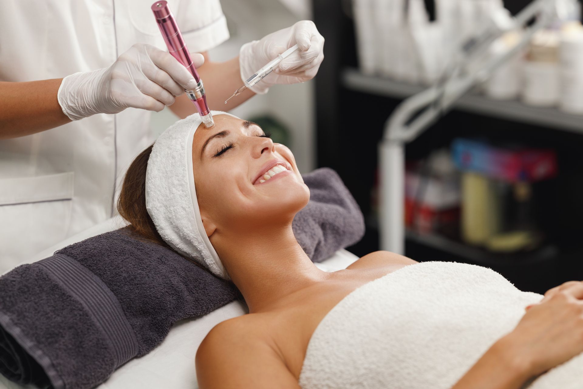 a woman is smiling while getting a treatment on her face