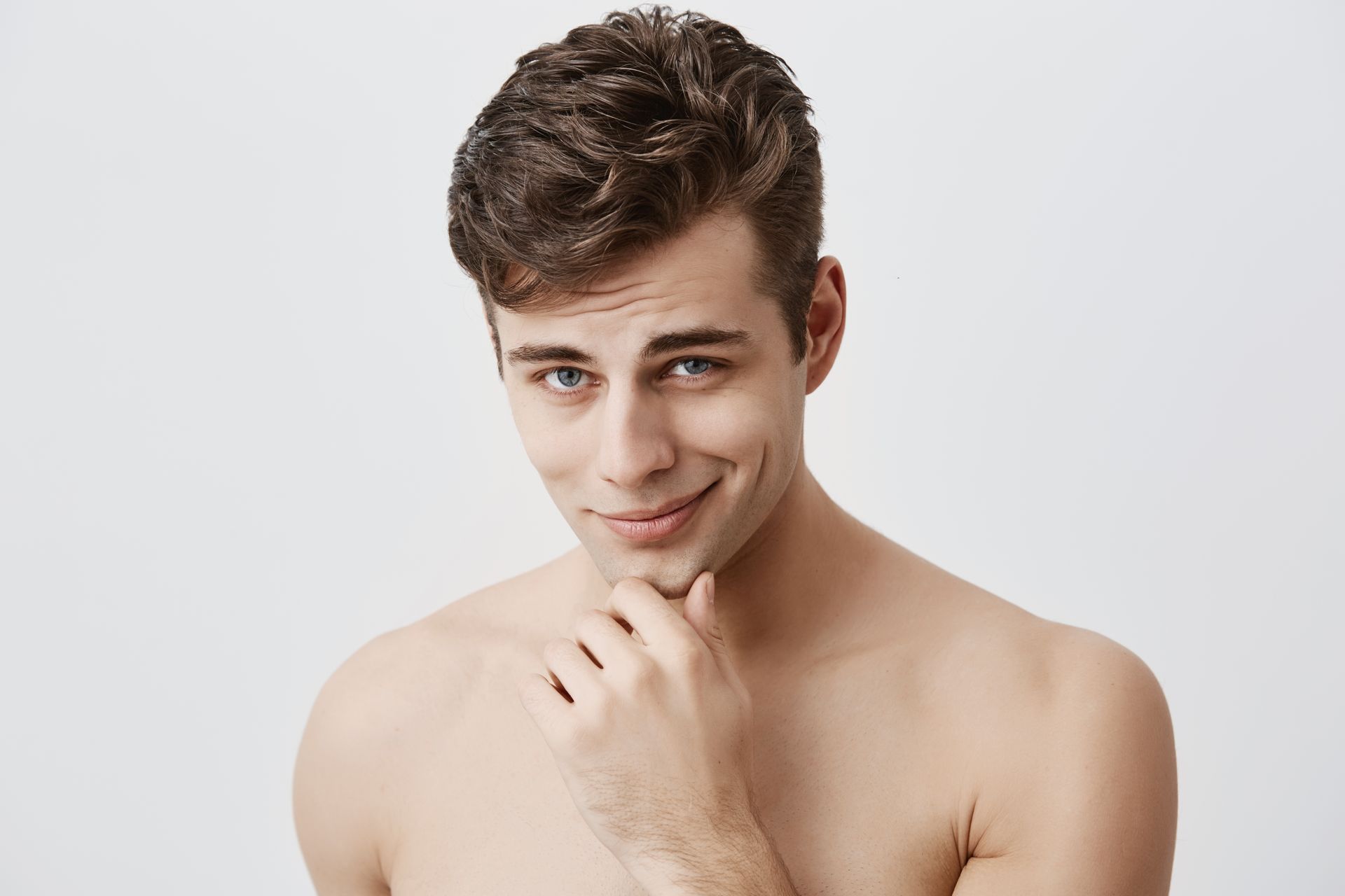 a shirtless man is smiling with his hand on his chin