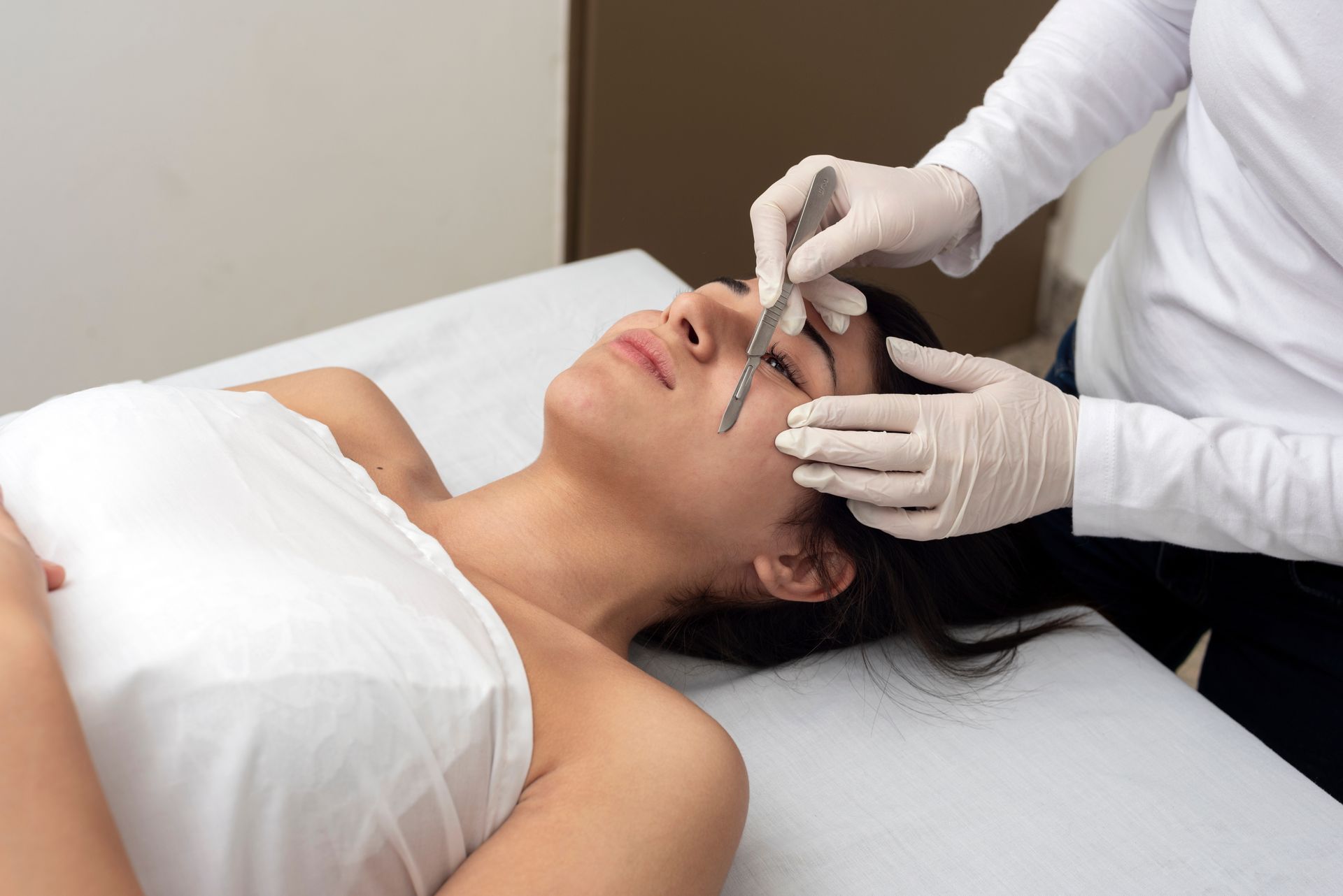 a woman is getting a facial treatment with a scalpel