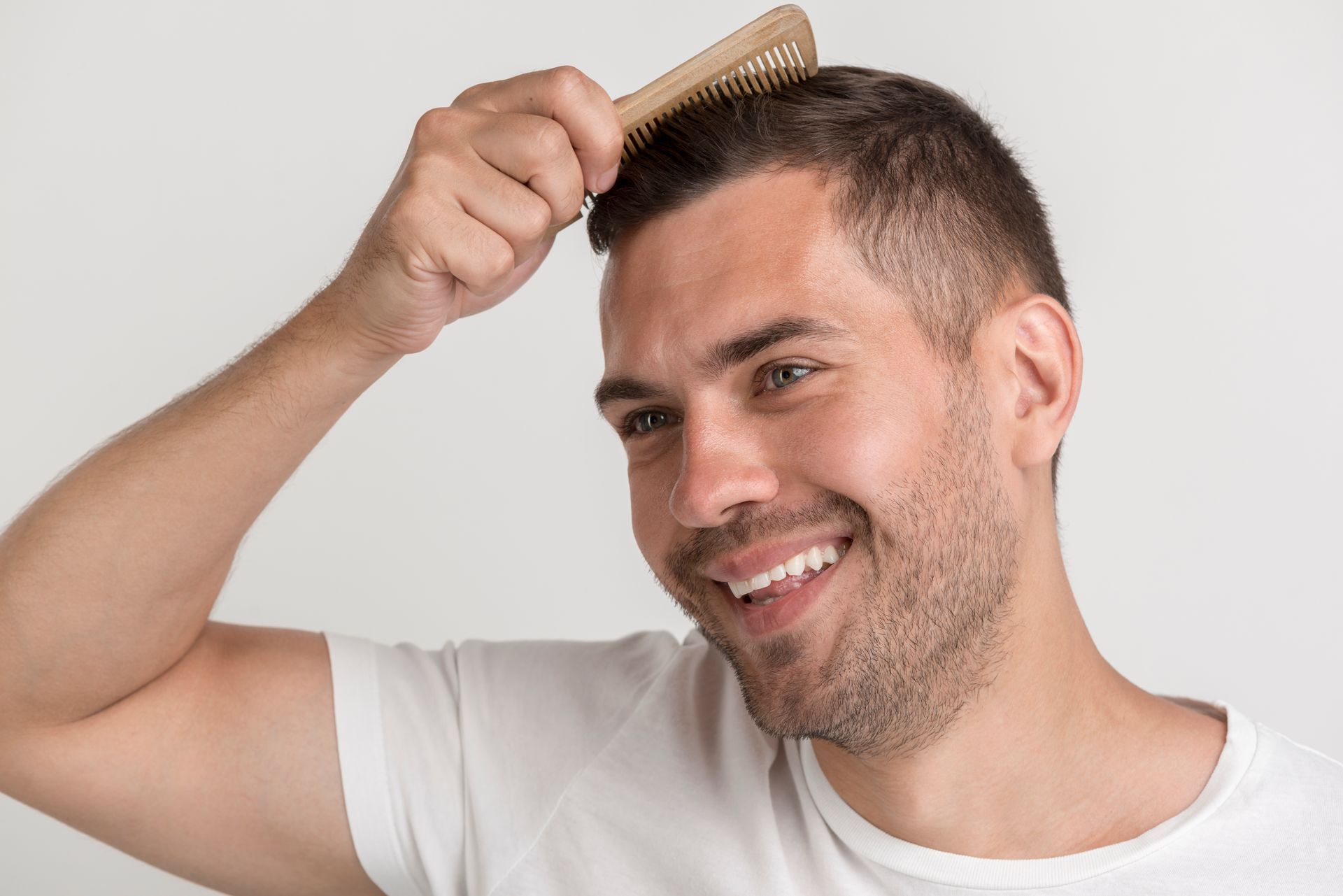 a smiling man is brushing his hair with a wooden comb