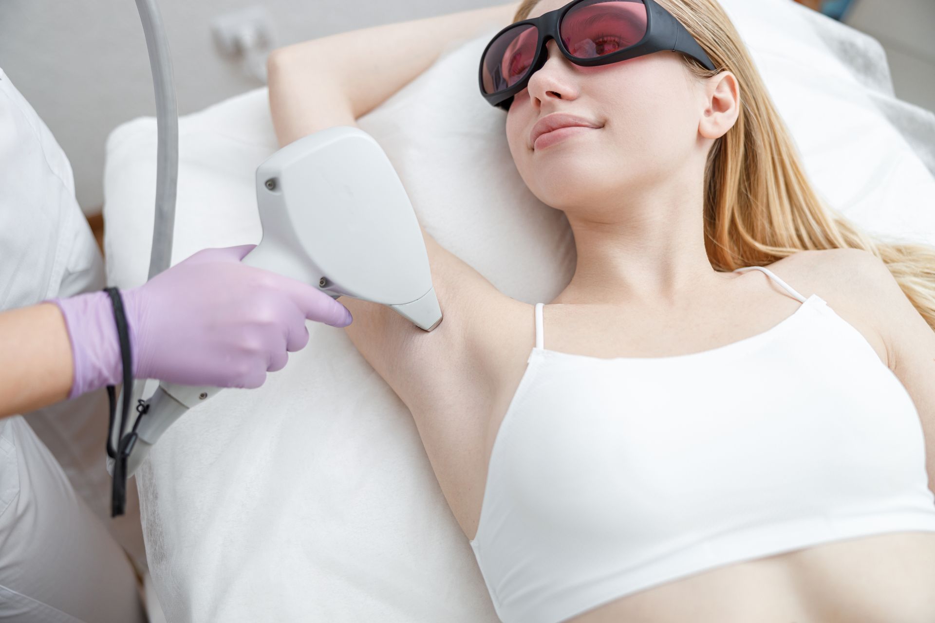 a woman wearing sunglasses is getting her underarm hair removed