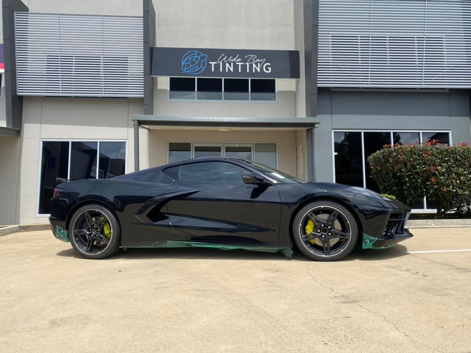 Black sports car with tinted windows parked in front of a tinting shop — Wide Bay Tinting in Kensington, QLD