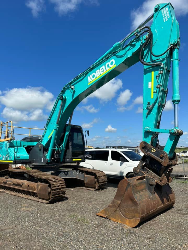 Excavator next to a white van in a dusty outdoor setting — Wide Bay Tinting in Kensington, QLD
