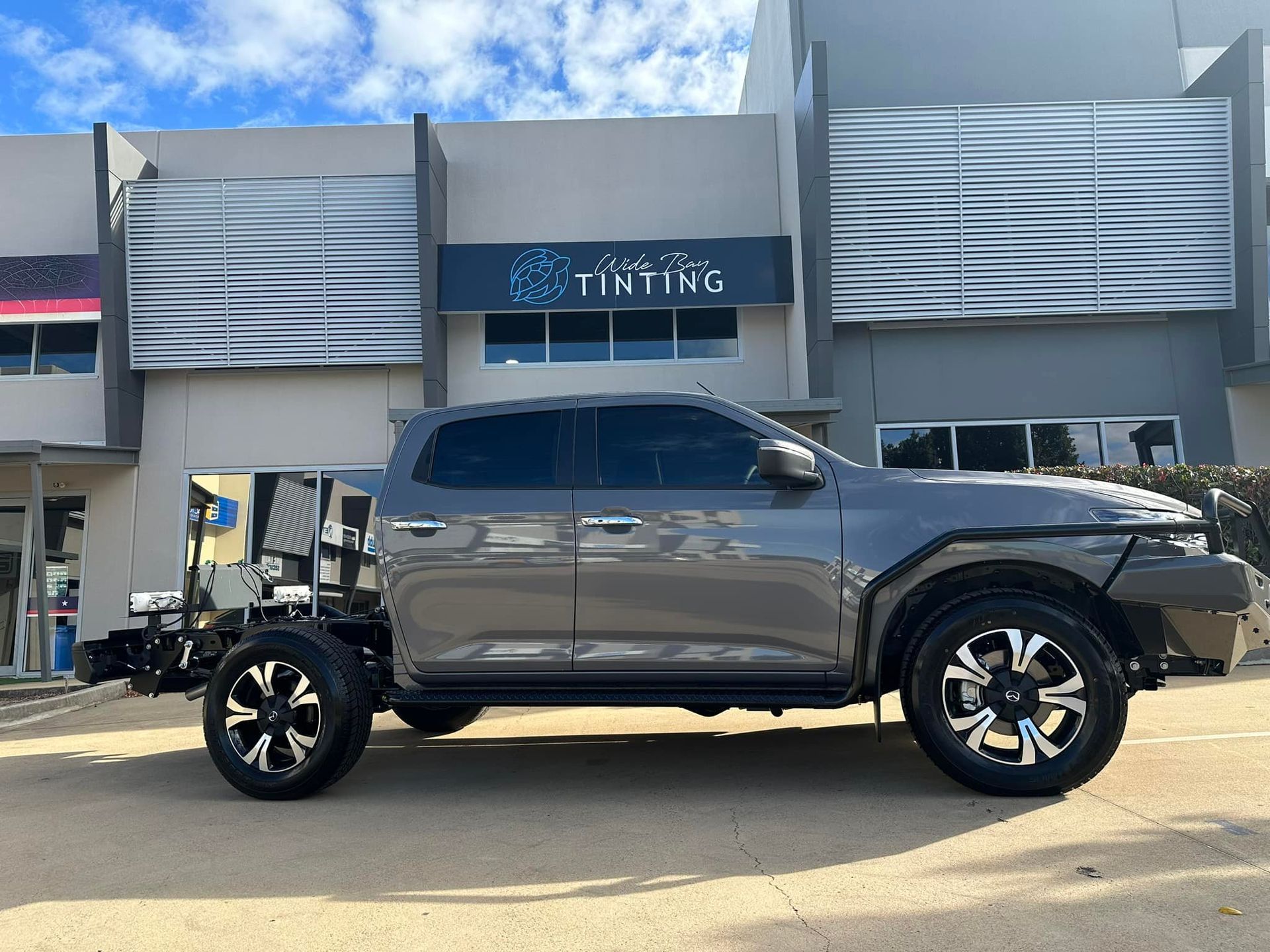 Gray pickup truck parked outside a tinting business, with large wheels and tinted windows — Wide Bay Tinting in Kensington, QLD