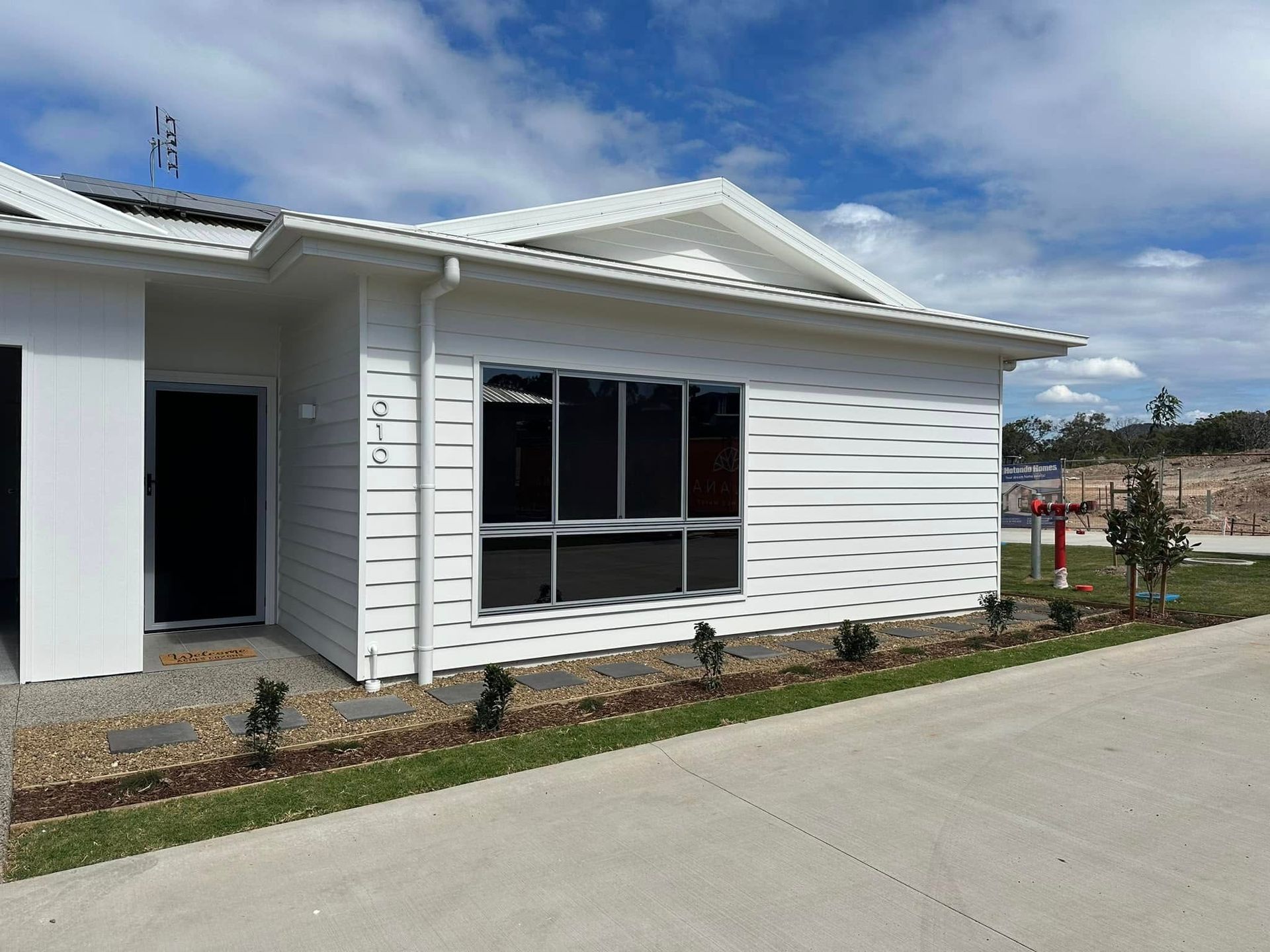 White House With Dark Windows, Gravel Bed, Green Grass, and Blue Sky — Wide Bay Tinting in Kensington, QLD