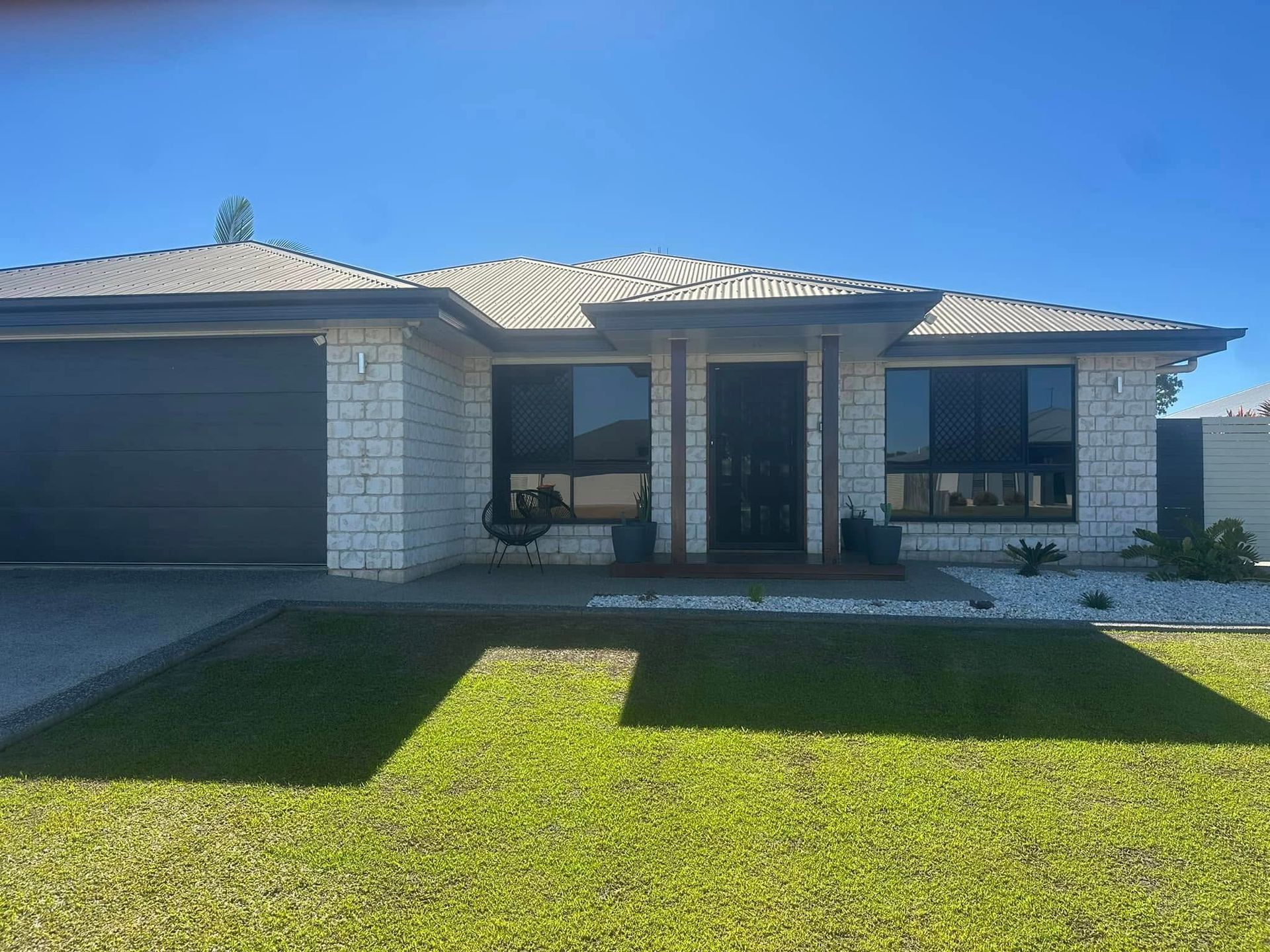 House with light brick facade, dark garage door — Wide Bay Tinting in Kensington, QLD