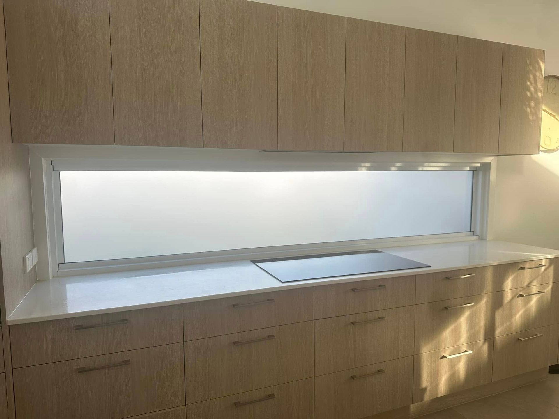 Modern kitchen with light wood cabinets, white countertops, and frosted window — Wide Bay Tinting in Gin Gin, QLD
